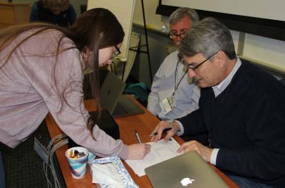 Sophie Smyth, captain of of the two Cranston High East teams, signs to verify the results of an early round in the competition.