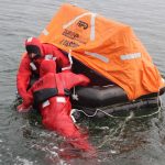 Commercial fishermen practice getting into a life raft.