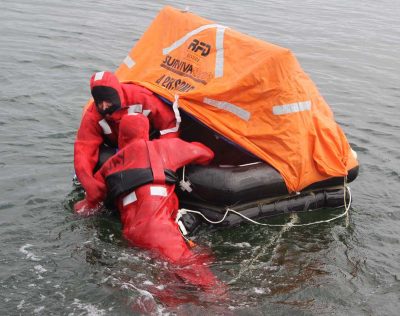 Commercial fishermen practice getting into a life raft.