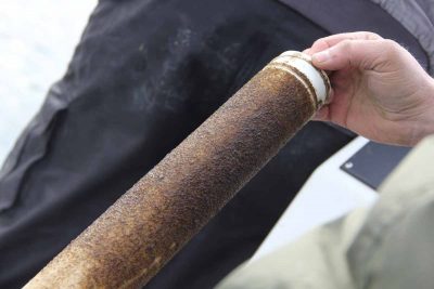 Pinhead-sized kelp seed is imbedded onto string and wrapped around PVC pipe before planting.