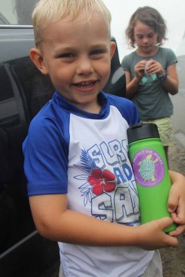 William Aspinwall shows the "Protect Our Wildlife: Break the Single-Use Plastic Habit" sticker on his water bottle after he and his family picked up trash at Bluff Point State Park on Aug. 1.