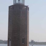 A student sits beside Avery Point lighthouse.