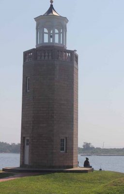 A student sits beside Avery Point lighthouse.
