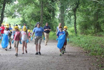 Mystic Aquarium summer campers head out on the main trail at Bluff Point State Park with trash bags and gloves to pick up trash.