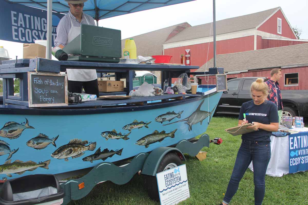 Chef Charlie Bailow prepares scup on the Food Boat while Kate Masury lists the ingredients of the samples served at the Lyme Farmers Market.
