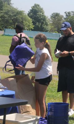 Courtney Ratti, 11, empties trash she collected during the cleanup into a large bag.
