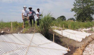 Sam Koeck, left, worked at the site with Sacred Heart University seniors Jeffrey Young, center, and Adrian Nelson, to lay mesh made of potato starch to secure soil at the site.