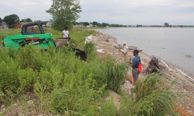Chris Hauser moves compost and sand with a backhoe as Adrian Nelson, second from left, Sam Koeck, center, and Jeffrey Young spread the material around the core log.