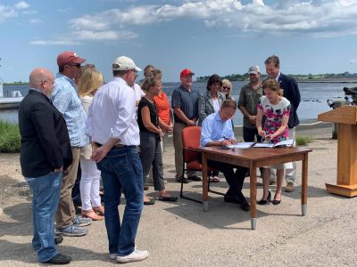 Gov. Lamont signs the Shellfish Restoration Bill on July 23 as legislators and industry members look on.