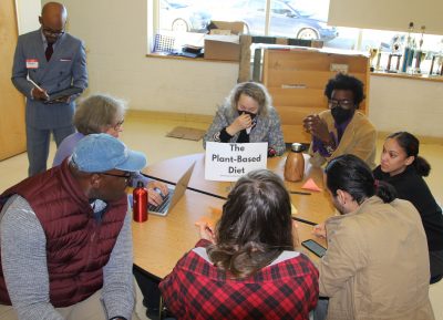 The plant-based diet group discusses the health and environmental benefits of avoiding meat consumption as astist Raheem Nelson captures the discussion in images on his iPad.
