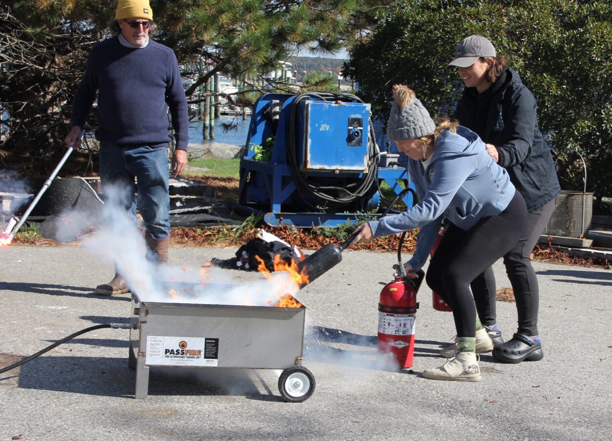 A participant directs a fire extinguisher on a fire during a training drill.