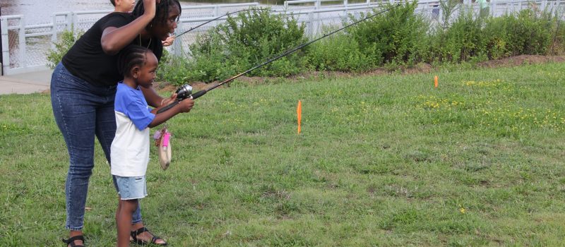 Volunteer Bobbi Brown, left, shows Anthony Leggitt, 5, how to cast a fishing rod during the CT Sea Grant-Groundwork Bridgeport "Let's Go Fishing" event Aug. 19 on Knowlton Park on the Pequonnock River.