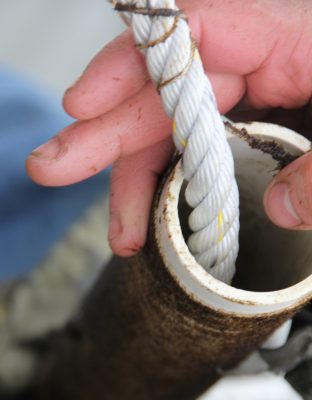 Seeded string is wound off a spool onto a line that will be suspended below the sea surface to grow kelp